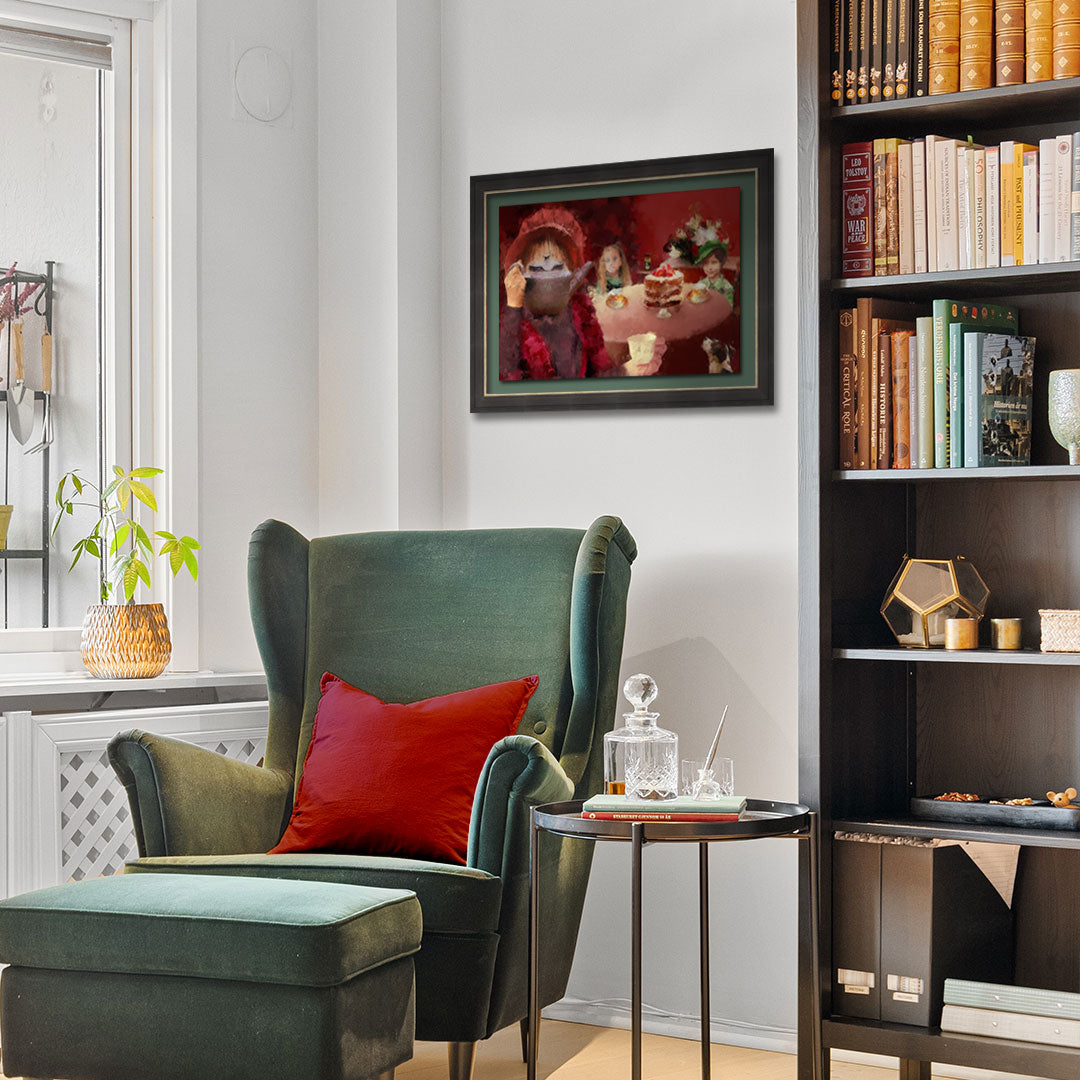 A framed art print depicting a tea party hangs on a white wall in a cozy living room setting with a green armchair, red accent pillow, and a dark bookshelf.